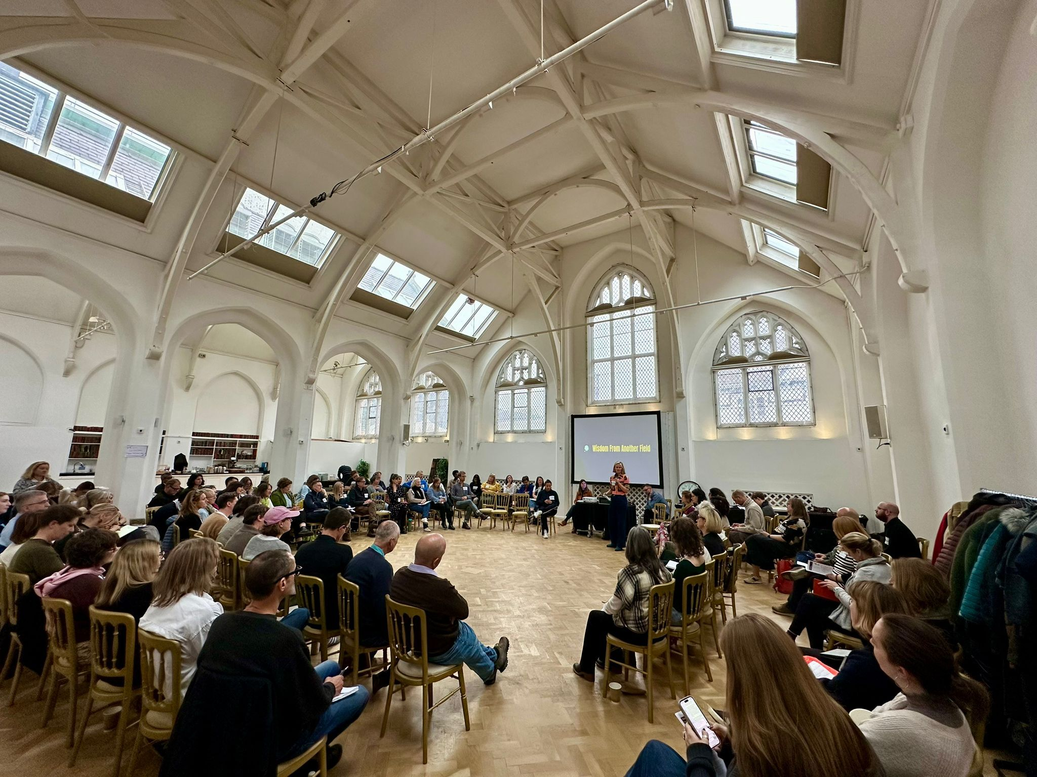 Photo of around 100 people sitting in a large circle